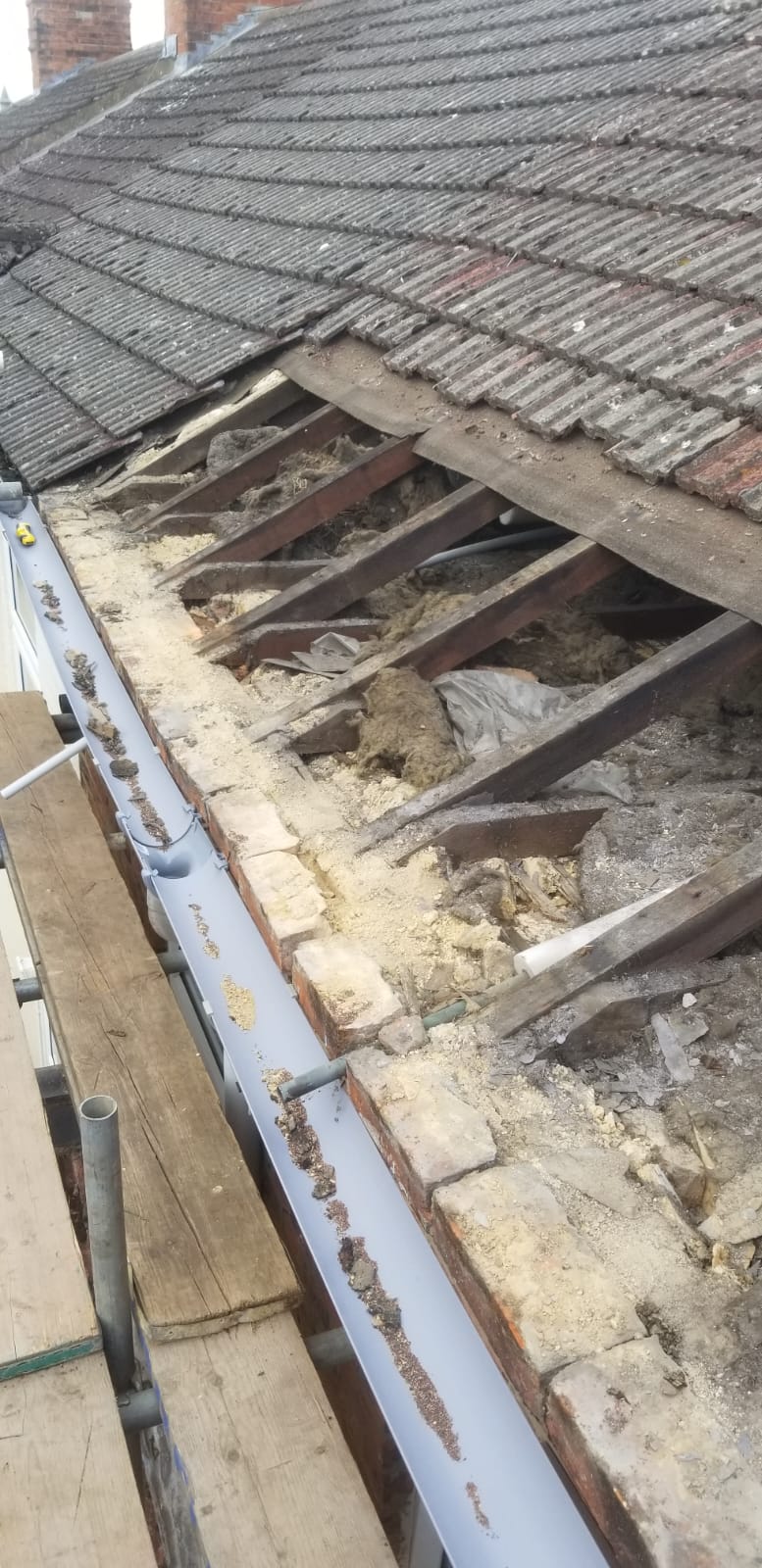 A storm-damaged roof being made safe