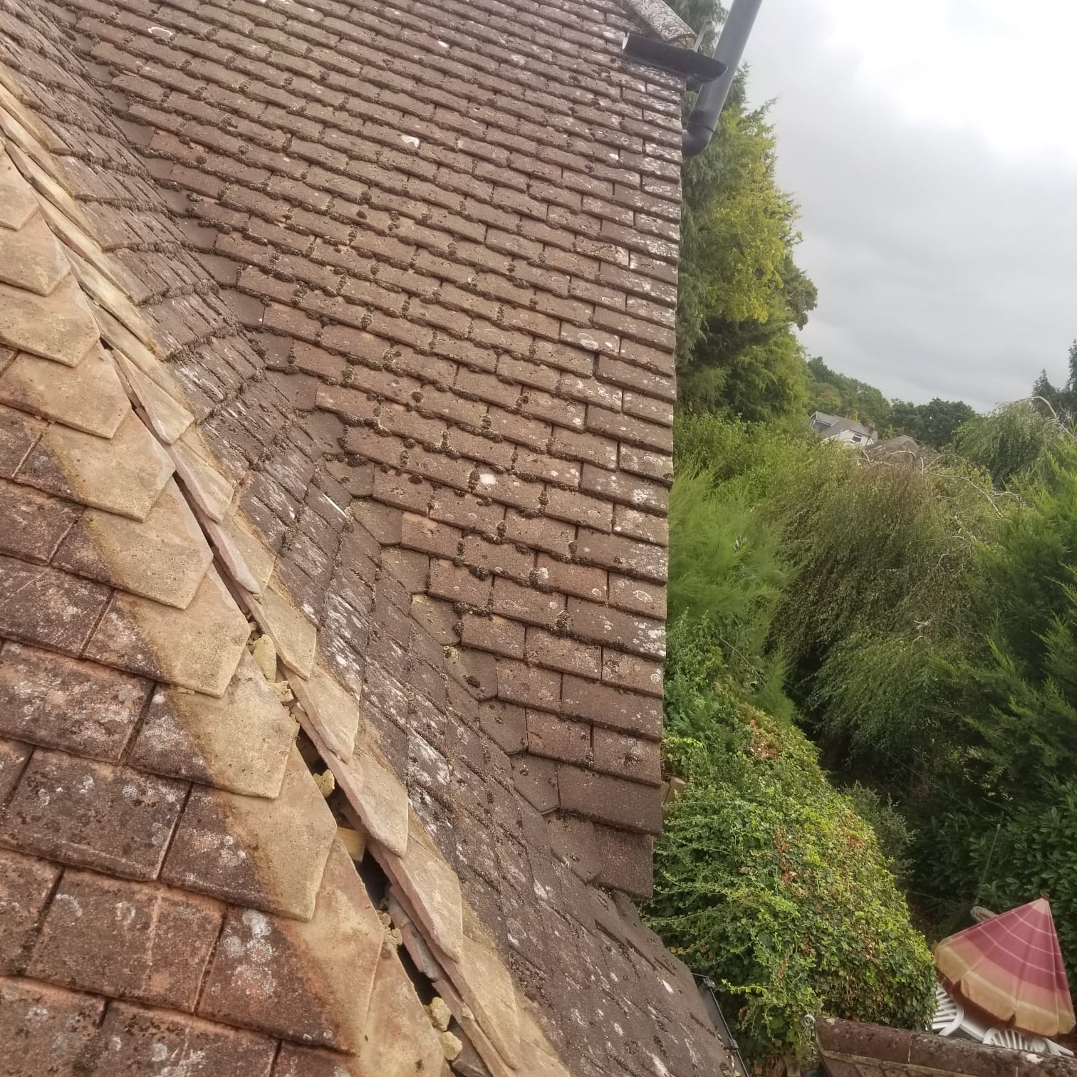 Slipped and damaged tiles on a weathered tiled roof awaiting repair
