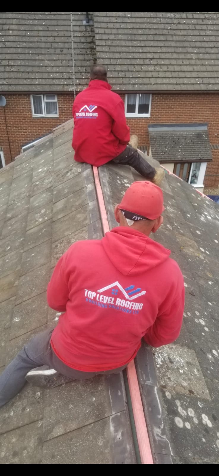 Two Top Level Roofing team members tiling a roof ridge