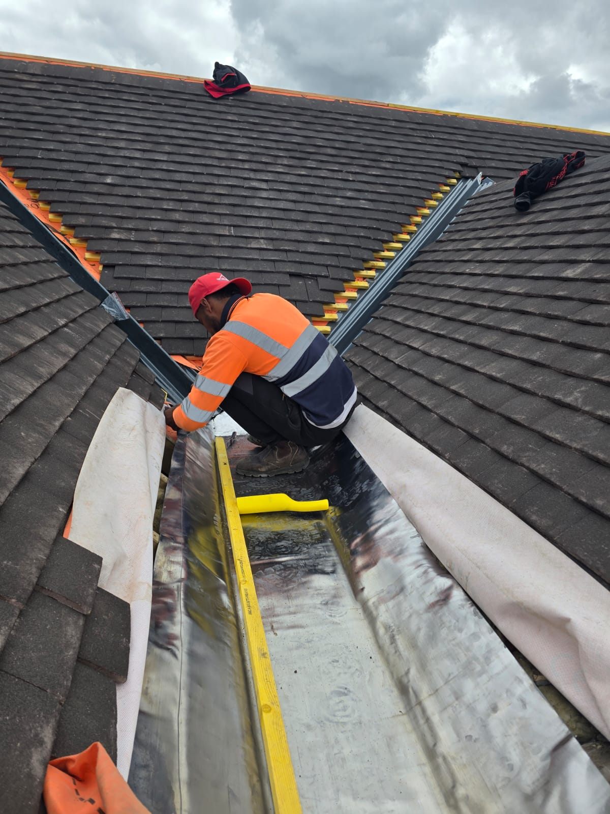 A roofer fitting a new lead valley between tiled slopes by Top Level Roofing & Building Solutions