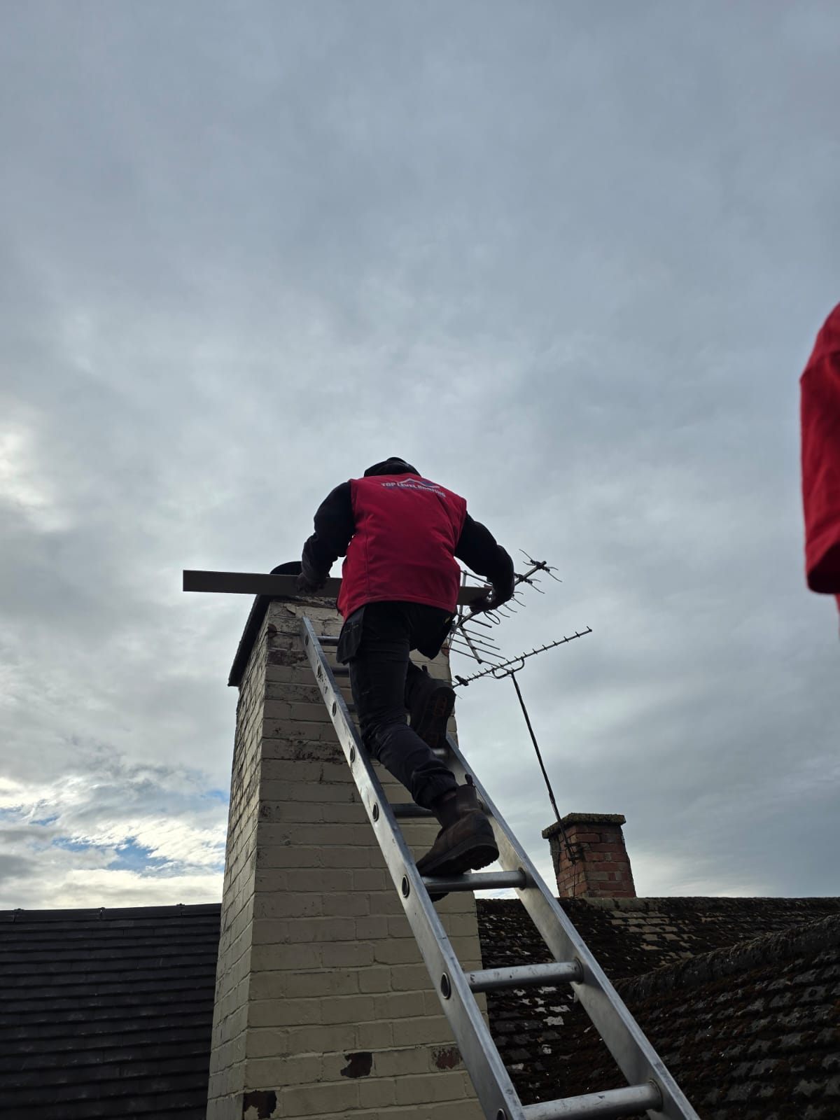 A Top Level Roofing roofer climbing to a brick chimney stack