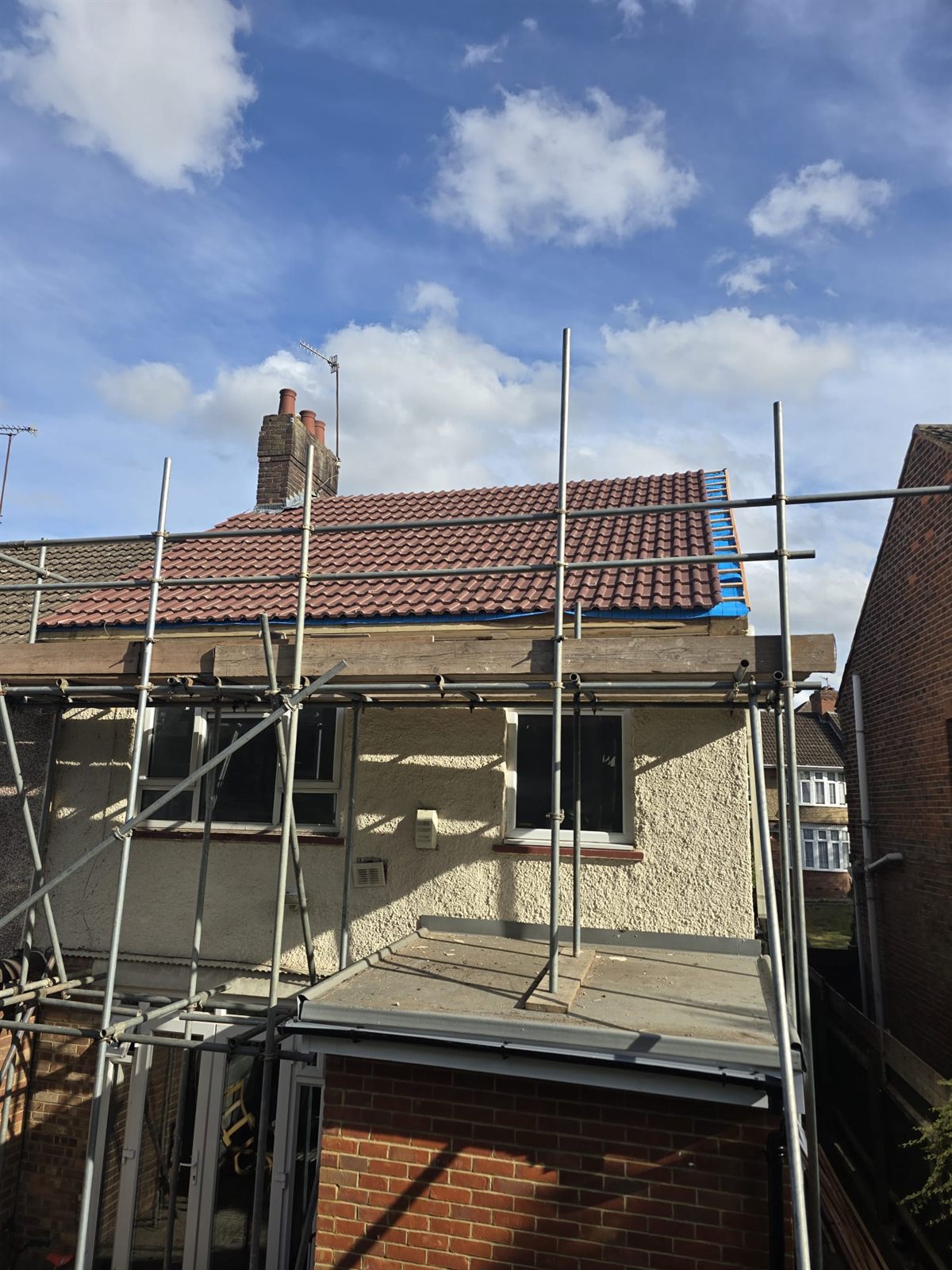 A finished new tiled roof pitch against a blue sky by Top Level Roofing & Building Solutions