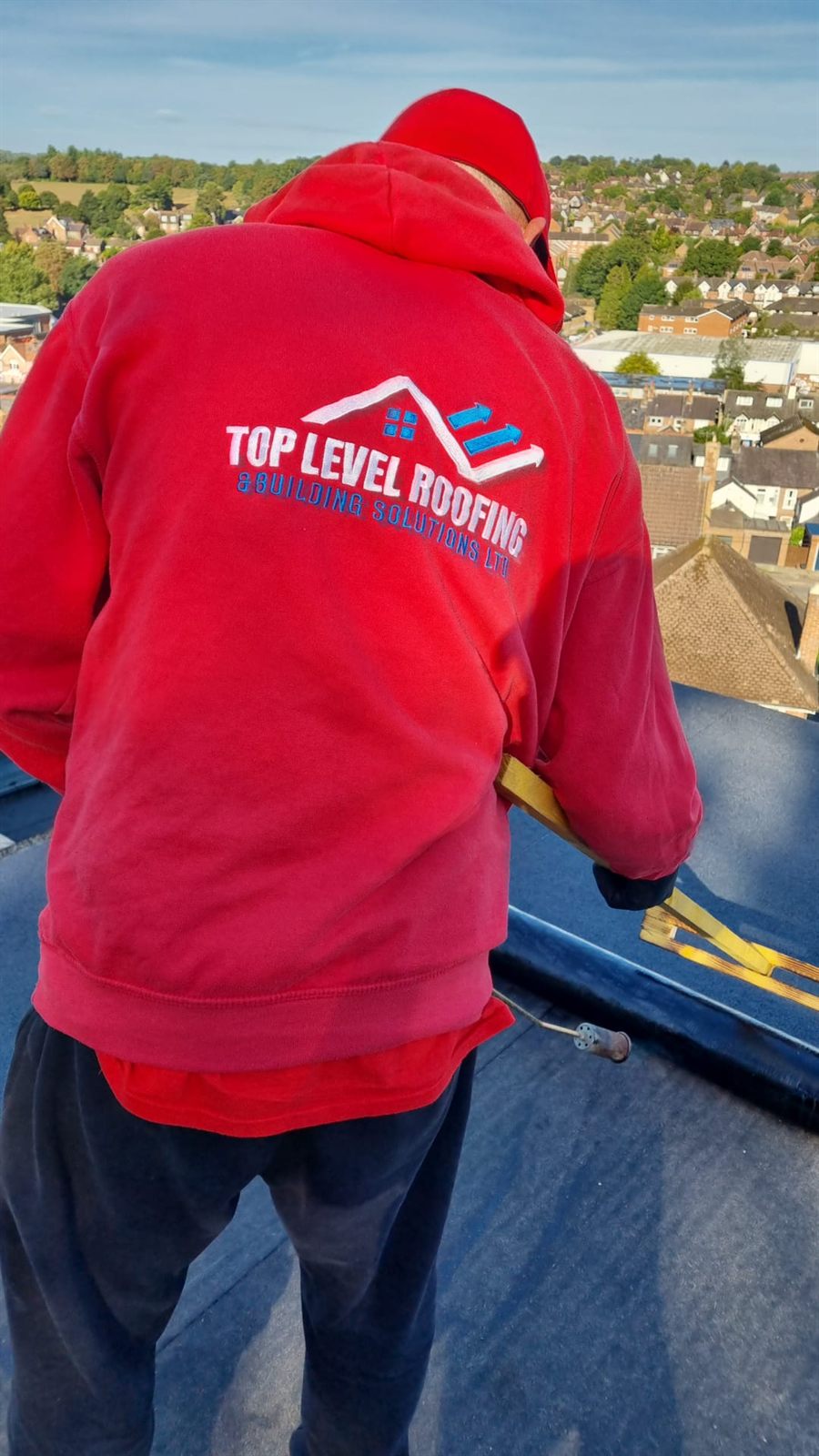 A Top Level Roofing roofer on a completed flat roof overlooking the town
