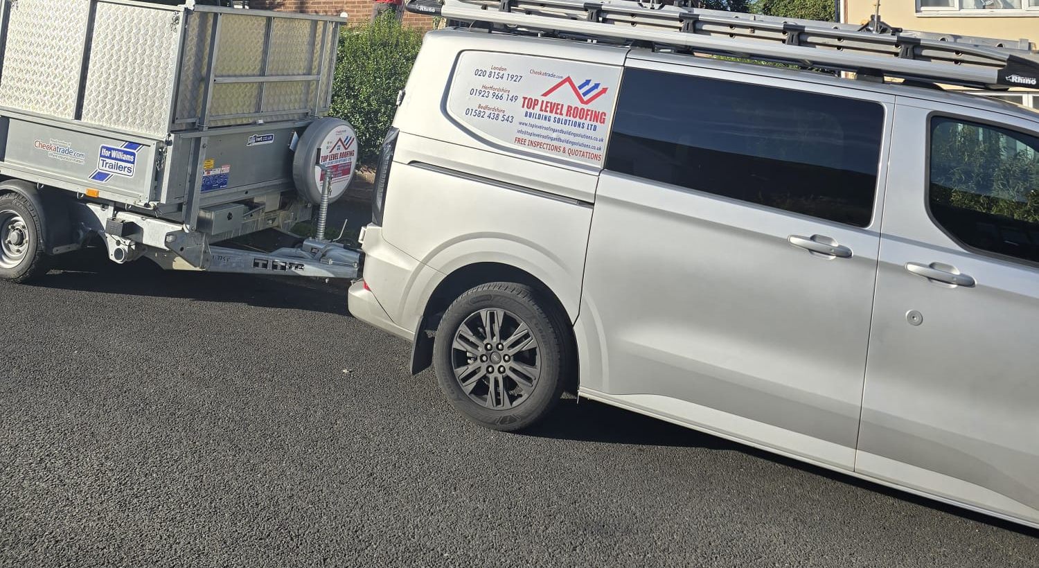 A branded Top Level Roofing van and trailer on a residential street